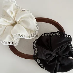 Detail of handmade lace fabric hair scrunchies in black and ivory with scalloped edges