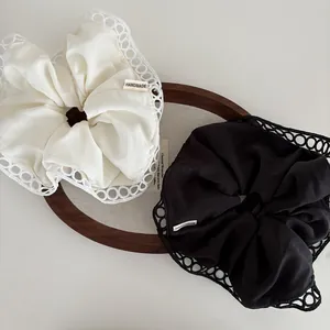 Detail of handmade cream and black scrunchies with intricate lace edges on a tray