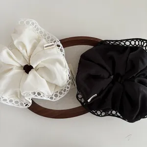 Detail of two handmade scrunchies with intricate hollow lace edges on a wooden display