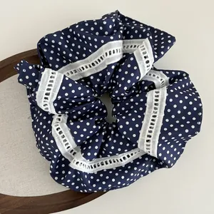 Detail eines dunkelblauen Polka-Dot-Haargummis mit feiner weißer Spitzenborte