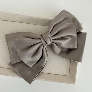 Elegant large triple-layer grey satin bow hair clip featuring a secure spring barrette