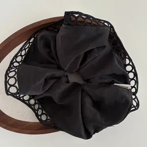 Macro detail of black fabric hair scrunchie with lace trim and handmade tag