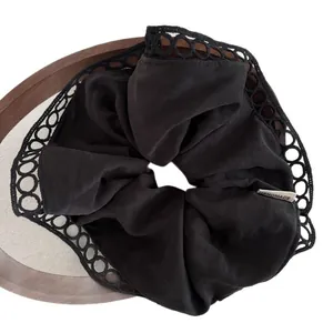 French style black fabric scrunchie with lace trim and handmade label on wood tray