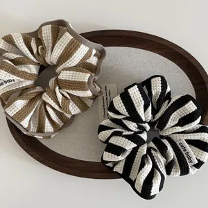 Detail of striped waffle fabric scrunchies with cute baby labels in a wooden tray