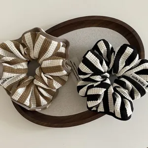 Detail of striped waffle knit scrunchies with cute baby labels in a wooden tray