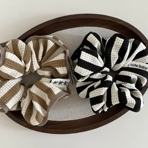 Close-up of striped waffle fabric scrunchies with white labels in a wooden tray