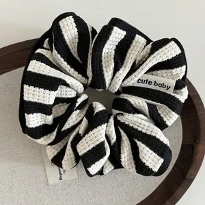 Close-up of black and white striped scrunchie with soft waffle texture and fabric label