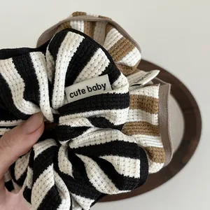 Striped waffle fabric scrunchie set with cute baby label held by hand on wooden plate