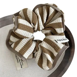 Striped waffle knit scrunchie with cute baby tag shown on a vintage wooden tray