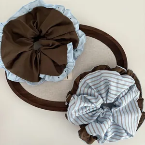 Blue and brown striped ruffled scrunchies set on a wooden tray for sweet hairstyling