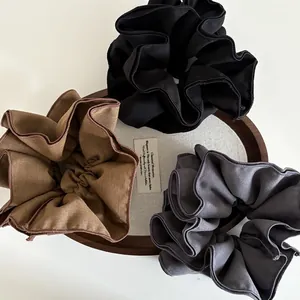 Dettaglio di elastici per capelli in tessuto plissettato nei colori nero e marrone