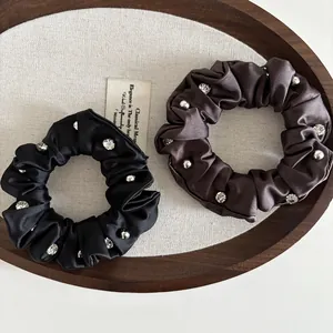 Detailed shot of satin scrunchies with crystals and silver beads on wooden tray