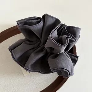 Dettaglio di un elastico per capelli arricciato in tessuto twill viola scuro