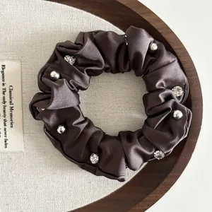 Detailed view of dark brown satin scrunchie featuring luxury rhinestones and beads