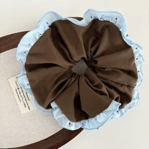 Brown fabric scrunchie with light blue polka dot ruffle edge for elegant ponytails