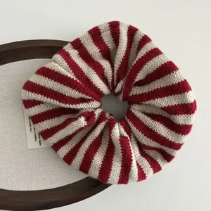 Detailed macro shot of red and white striped knit scrunchie on a wooden tray