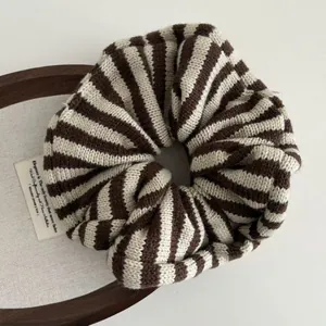 Detailed close-up of knitted scrunchie with brown and beige stripes on a wooden tray