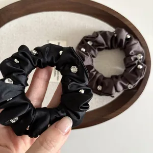 Set of two satin scrunchies in black and brown featuring elegant rhinestone embellishments