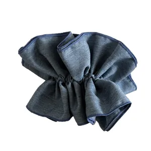Scrunchie in denim blu con bordi a balze plissettate su uno sfondo bianco pulito