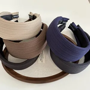 Detail of handmade wide headbands in Morandi colors with textured fabric on wooden tray