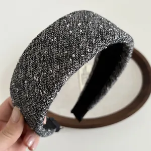 Gros plan d'un serre-tête large en tweed noir et gris avec texture scintillante