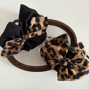Detail of large leopard print and black silk bow hair claws on a wooden tray