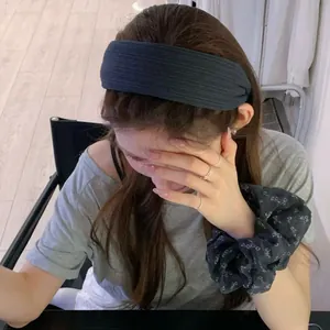 Detail of dark grey ribbed knit headband and matching floral scrunchie on model