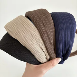 Close-up of four wide headbands featuring ribbed texture in black, beige, brown and navy blue