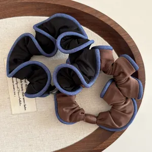 Detailed close-up of ruffle hair scrunchies in black and brown within a wooden tray