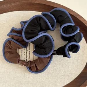 Close-up of retro black and brown fabric scrunchies with elegant blue contrast piping