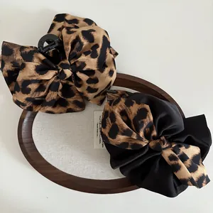 Detail of oversized leopard print and black contrast bow hair claws in a wooden tray