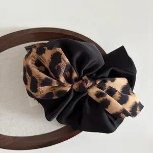 Detailed view of a large leopard print and black silk bow hair claw clip for women