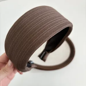 Detail of brown wide padded headband with fine striped knit texture and soft fabric finish