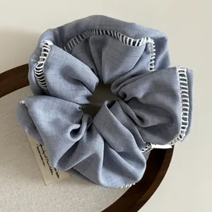 Detailed shot of light blue fabric scrunchie with white lace trim on wooden tray