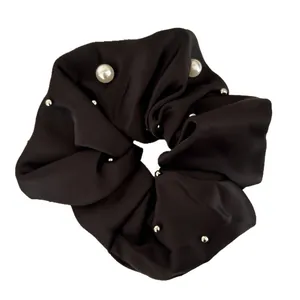 Elegant black satin oversized scrunchie with white pearls and silver studs on white background