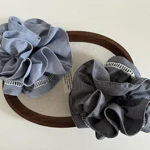 Detail of blue and grey fabric scrunchies with white lace edges on a wooden tray