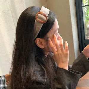 Bruine brede stoffen haarband met harsring versiering op een vrouwelijk model