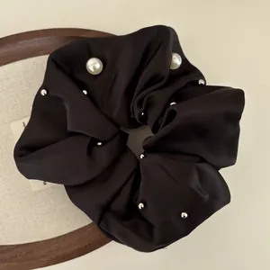 Elegant black satin scrunchie with white pearls and silver studs for sleek bun hairstyles