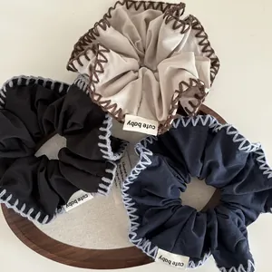 Three-piece set of handmade oversized scrunchies with stitching detail and cute baby label