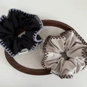 Detailed view of handmade scrunchies with thick contrast stitching on a wooden tray