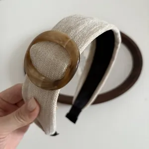 Brede beige stoffen haarband met barnsteenkleurige ring en retro-esthetische look