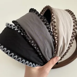 Close-up of wide fabric headbands featuring retro hand-stitched overlock edge details