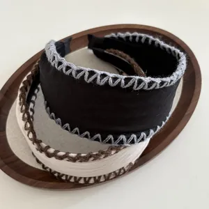 Detail of wide retro headbands with hand-stitched edges in black and beige tones