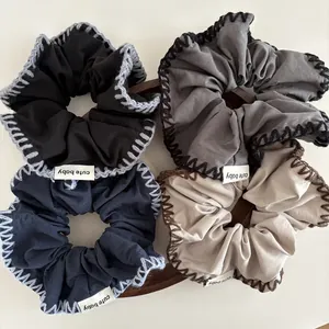 Knitted fabric scrunchies with contrast stitch edging in black, grey, navy, and beige colors