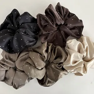 Detail of five satin hair scrunchies with shiny crystals in diverse elegant colors