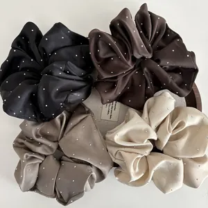 Detail of four satin scrunchies in earth tones with sparkling rhinestone embellishments