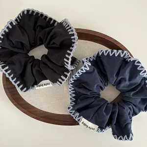 Set of minimalist knitted scrunchies in black and dark grey with contrast whipstitch edge