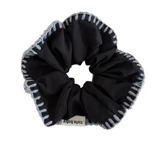 Handcrafted black cotton scrunchie with grey hand-stitched edges and cute baby label