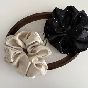 Detail of satin hair scrunchies in black and beige with sparkling rhinestones decoration