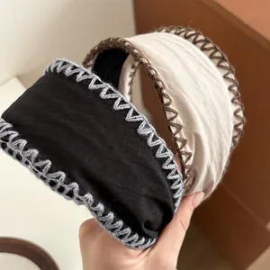 Wide knit headband with manual stitching in black and beige, minimalist vintage style